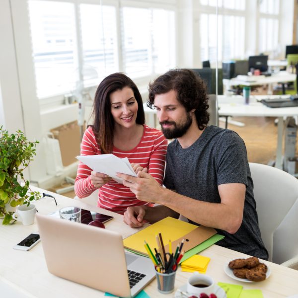 Male and female graphic designers interacting over document in office